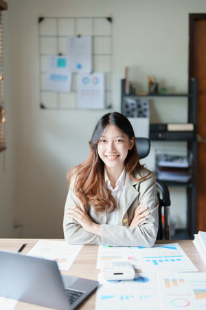 Portrait of a woman business owner showing a happy smiling face as he has successfully invested her business using computers and financial budget documents at work.の写真素材