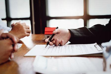 A couple is reading a home purchase contract before signing documents with a real estate agent.の写真素材