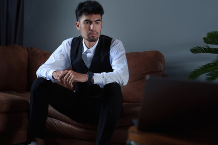 Portrait of a handsome, discreet Asian man sitting on the sofa using a computer.の写真素材