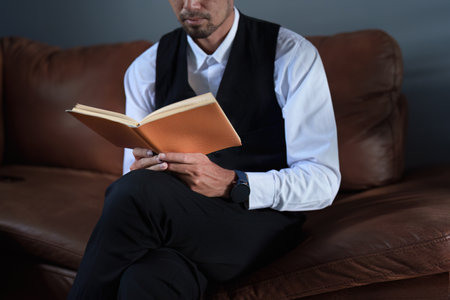 Portrait of a good looking Asian man sitting on the sofa reading a book.の写真素材