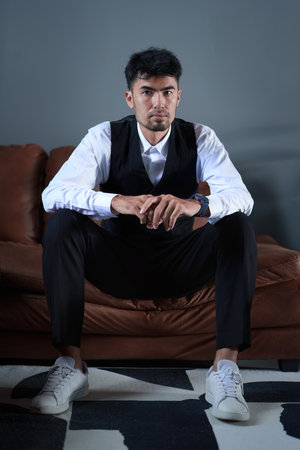 Portrait of a good looking Asian man sitting on the sofa.の写真素材