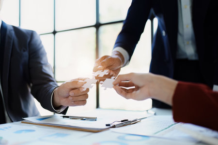 Business people with jigsaw puzzle pieces in office, Successful teamwork and partnership conceptの写真素材
