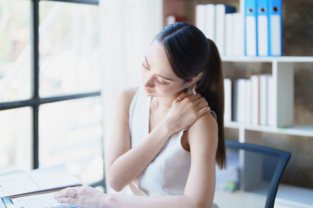 Portrait of young Asian female representative showing shoulder pain from sitting for a long time.の写真素材