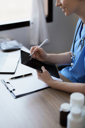 Portrait of a female doctor using a tablet computer and a document analyzing a patients condition before treatingの写真素材