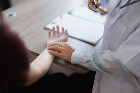 Portrait of a female doctor using a stethoscope to check the pulse of an elderly patientの写真素材