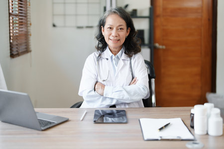 Portrait of a female doctor using a computer and a document analyzing a patients condition before treatingの写真素材