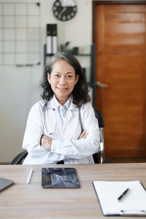 Portrait of a female doctor using a computer and a document analyzing a patients condition before treatingの写真素材