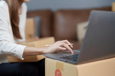 Starting small business entrepreneur of independent young Asian woman online seller is using computer and taking orders to pack products for delivery to customers. SME delivery concept.の写真素材