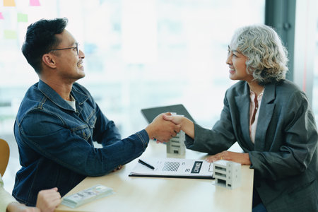 The banks Mortgage Officers shake hands with customers to congratulate them after signing a housing investment loan agreement.の写真素材