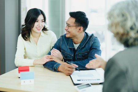 Guarantee Insurance Sign a contract, couple a smiling couple is signing a contract to invest in real estate with the Mortgage officer with the bank.の写真素材