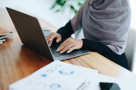 A beautiful Muslim woman showing a smiling face in the morning using computers and documents working at the office.の写真素材