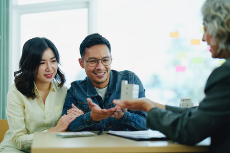 Guarantee Insurance Sign a contract, couple a smiling couple is signing a contract to invest in real estate with the Mortgage officer with the bank.の写真素材