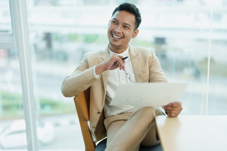 Male entrepreneur, business owner or Asian male businessman sitting and holding documents at a...