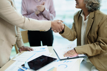 Asian entrepreneurs handshakes to congratulate the agreement between the two companies to enhance...