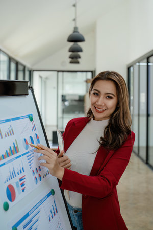 portrait of Beautiful young asian businesswoman presents business profits to colleagues at meeting,...