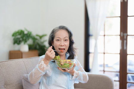 Portrait of an elderly Asian woman taking care of her health by eating saladの写真素材