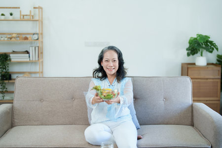 Portrait of an elderly Asian woman taking care of her health by eating saladの写真素材
