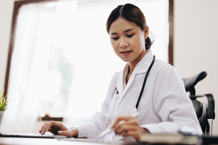 Portrait of an Asian female doctor using a computer and tablet to work.の写真素材