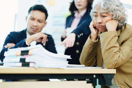 An image of an Asian male employee looking worried and sad about being scolded by his boss for failing to meet sales targets, concept of disappointment and failure in his career.の写真素材