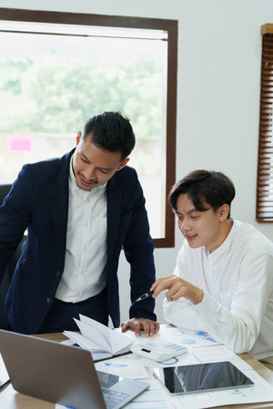Young economists or accountants or financiers and investors are reviewing budget documents and using computers to study impact and risk assessments on corporate investment management.の写真素材