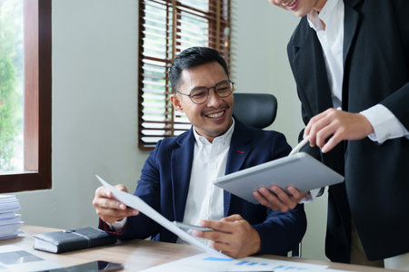 Concept of the impact of warring countries, male economists are using tablets to consult with marketing staff or accountants to adjust production and investment strategies to the current situation.の写真素材