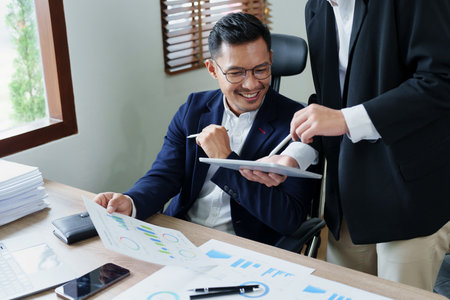 Concept of the impact of warring countries, male economists are using tablets to consult with marketing staff or accountants to adjust production and investment strategies to the current situation.の写真素材