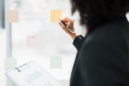 Beautiful young teen American African holding pen to note with planning working on financial document, tax, exchange, accounting and Financial advisor.の写真素材