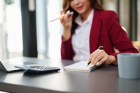Beautiful young teen asian businesswoman using computer and smartphone mobile with planning working on financial document, tax, exchange, accounting and Financial advisor.の写真素材