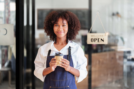 Startup successful small Beautiful American African owner sme beauty girl stand holding coffee cup in coffee shop restaurant, entrepreneur seller business concept.の写真素材