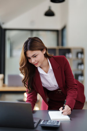 Beautiful young teen asian businesswoman using laptop computer and paperworks with planning working on financial document, tax, exchange, accounting and Financial advisor.の写真素材