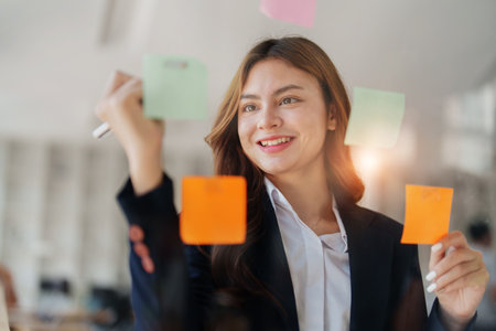 Beautiful young teen asian businesswoman using note pad thinking with planning working on financial document, tax, exchange, accounting and Financial advisor.の写真素材