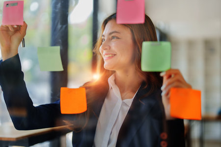 Beautiful young teen asian businesswoman using note pad thinking with planning working on financial...