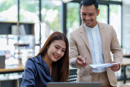startup business, portrait of two entrepreneurs using computers and financial budget documents to make marketing plans to increase profits.の写真素材