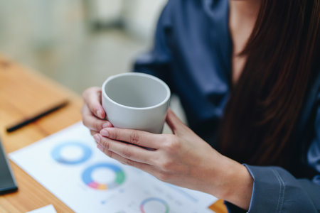 Portrait of a happy Asian woman smiling at her desk during the daytime coffee break.の写真素材