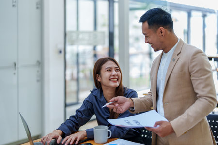 startup business, portrait of two entrepreneurs using computers and financial budget documents to make marketing plans to increase profits.の写真素材