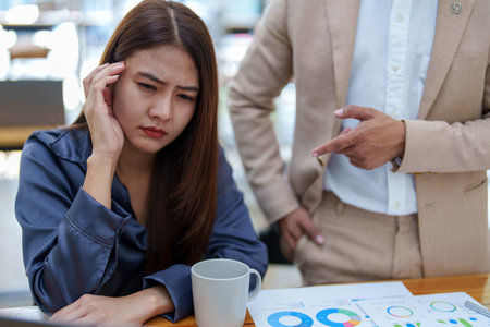 portrait of a female marketing worker showing a worried expression after being reprimanded by a male business owner for failing to meet the companys sales targets.の写真素材