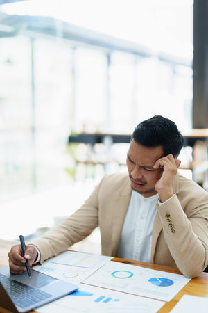 Portrait of sme business owner, man using computer and financial statements Anxious expression on...