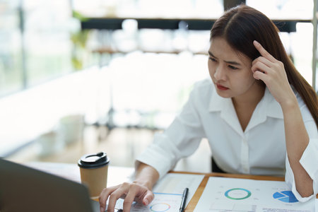 Portrait of sme business owner, woman using computer and financial statements Anxious expression on expanding the market to increase the ability to invest in business.の写真素材