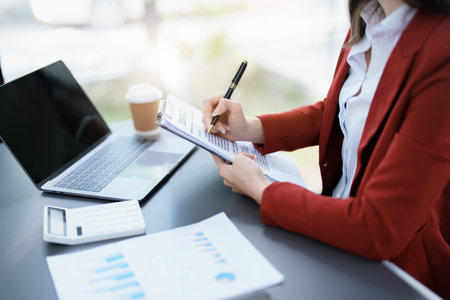 financial, Planning, Marketing and Accounting, portrait of Asian employee checking financial statements using documents and calculators at work..の写真素材