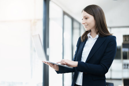 Excited businesswoman using computer laptop while in office, business conceptsの写真素材