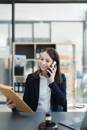 Portrait of a Asian woman lawyer studying lawsuit a for a client using smartphone , documents and computer to work before going to courtの写真素材