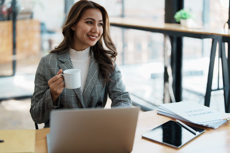 Portrait of a business woman talking on the computer and drinking coffee.の写真素材