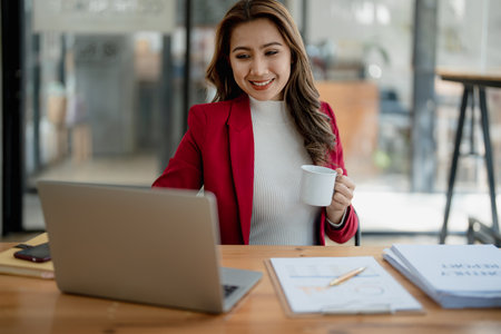 Portrait of a business woman talking on the computer and drinking coffee.の写真素材