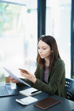 Portrait of a young Asian man showing a smiling face as she uses his phone, computer and financial...