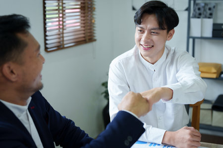 Portrait of two young Asian entrepreneurs congratulating them with smiling faces after successful investment negotiations.の写真素材
