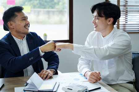 Portrait of two young Asian entrepreneurs congratulating them with smiling faces after successful investment negotiations.の写真素材