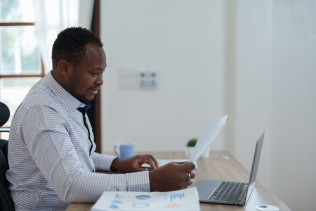middle aged man American African using computer laptop with planning working on financial document, tax, exchange, accounting and Financial advisor.の写真素材