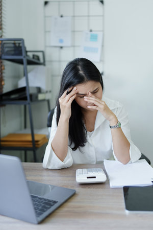 Portrait of sme business owner, woman using computer and financial statements Anxious expression on expanding the market to increase the ability to invest in business.の写真素材