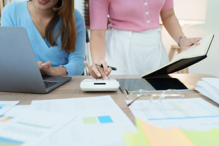 Financial analysts analyzing business reports on planned investment projects during corporate meeting discussions showcase successful teamwork with marketing plan, computers and calculators to work.の写真素材