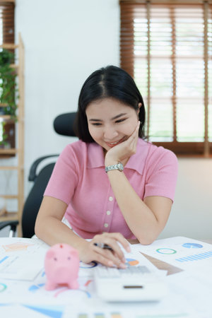 investment plan, young asian woman keep coin money in jar and using calculator to calculate savings.の写真素材